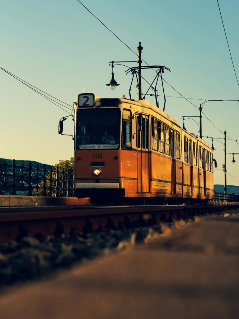 Iconic Budapest tram traveling on tracks at sunset, showcasing urban transport in Hungary.